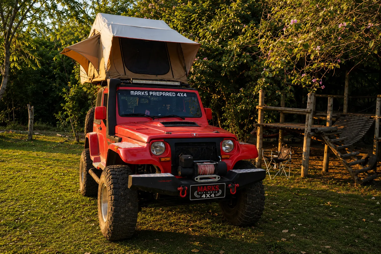 Troller vermelho com barraca de teto montada em área de camping